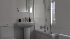 Et moderne badeværelse med vask, spejl, toilet og bruser.
