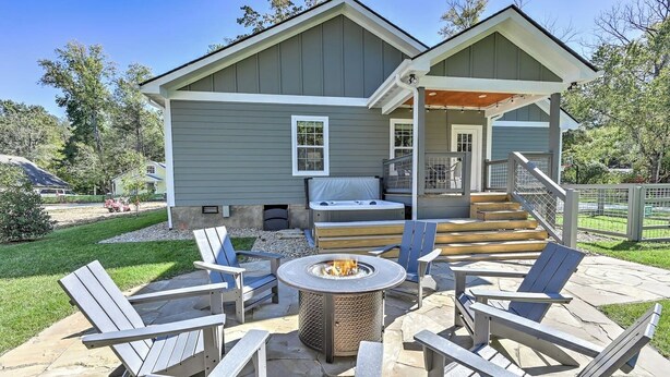 Une maison dotée d’un patio comprenant des fauteuils Adirondack, un foyer et un jacuzzi.