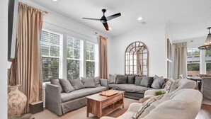 A spacious living room with a grey sectional sofa, a wooden coffee table, and a white armchair.
