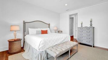 A bedroom with a bed, bedside tables, a bench, a dresser, and a door.
