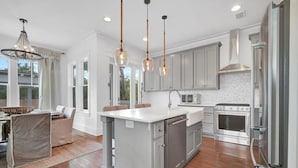 A modern kitchen with grey cabinets, stainless steel appliances, and a central island.