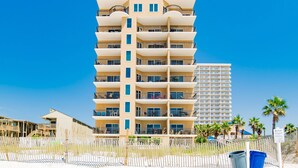 A multi-story hotel with balconies, located near a beach.