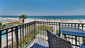 A balcony with a view of a beach and a pool.