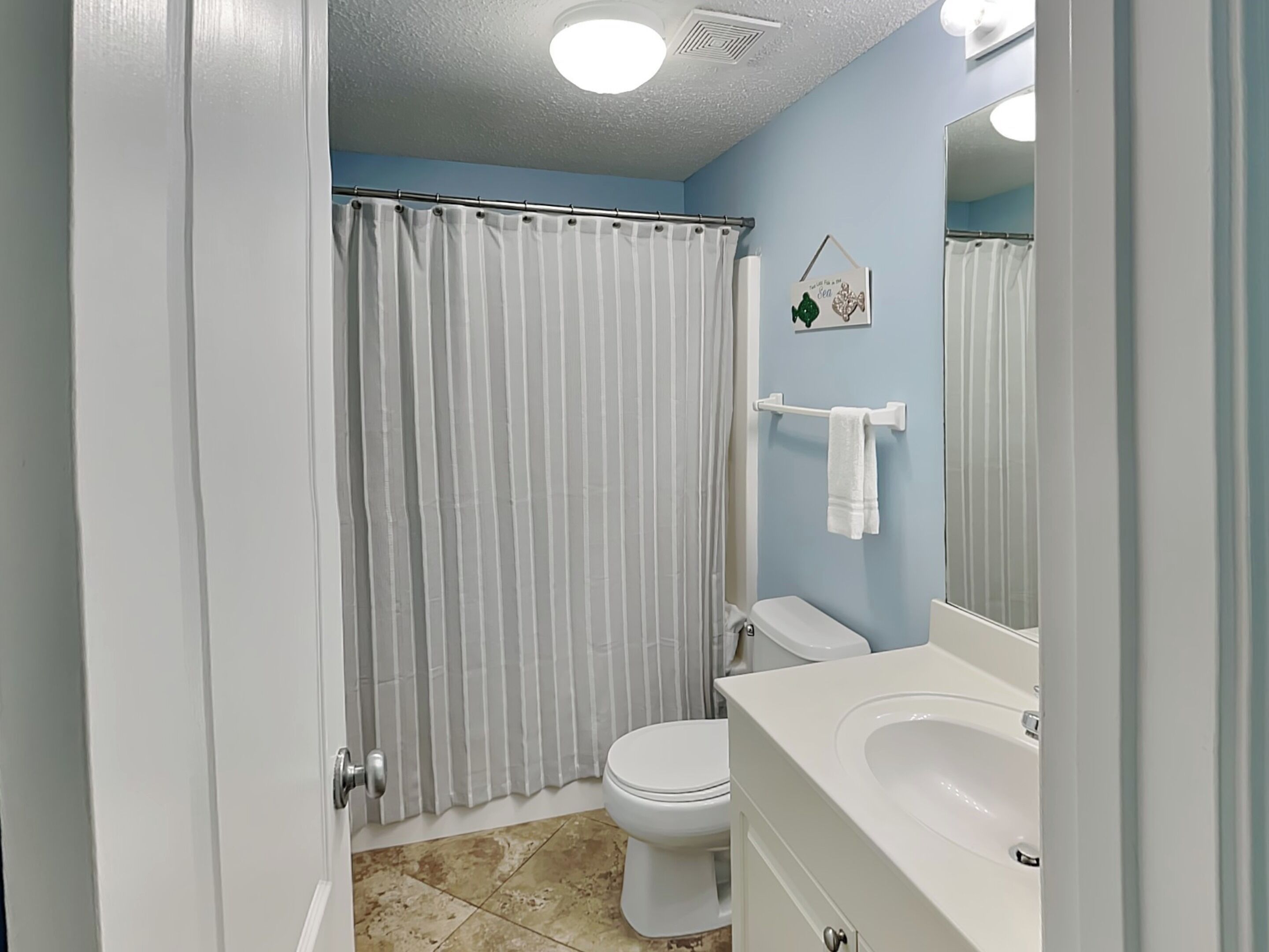 Un baño con inodoro, lavamanos y cortina de ducha.