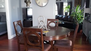 A dining area with a round wooden table and chairs, a wall clock, and a chandelier. - Cottage setup (New Bedford)
