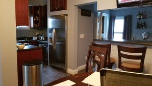 A kitchen with a stainless steel refrigerator, wooden cabinets, and a dining area with two wooden chairs. - Cottage setup (New Bedford)