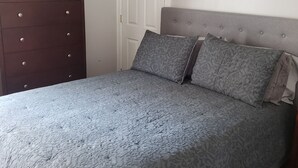 A bedroom with a bed, a dresser, a door, and a framed picture on the wall. - Cottage setup (New Bedford)