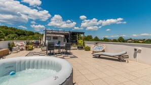 Eine Dachterrasse mit Whirlpool, Sitzgelegenheiten im Freien und einem Wohnwagen.