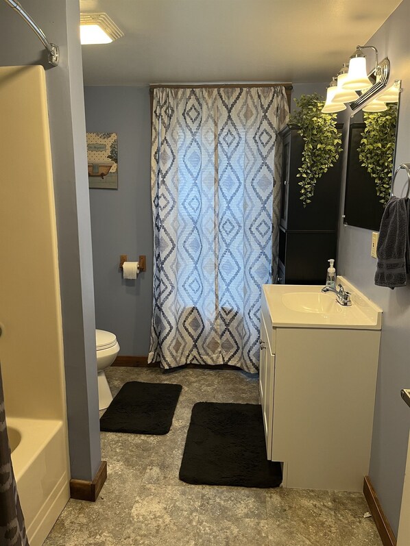 Un baño con cortina de ducha estampada, un lavabo con espejo y un inodoro.