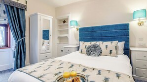 Ein Schlafzimmer mit Bett, Nachttischen, einem Kleiderschrank und einem Fenster mit Vorhängen.