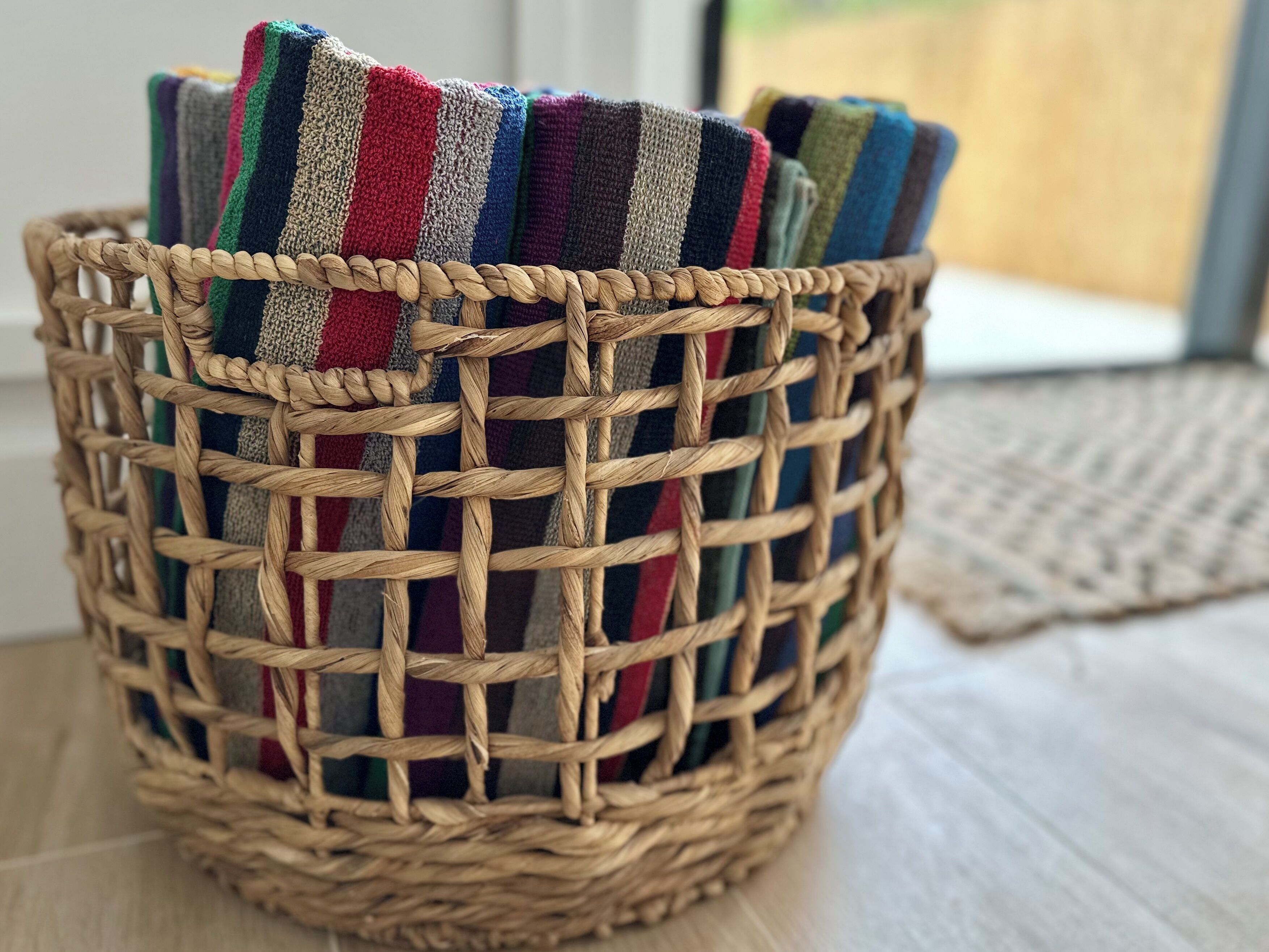 A woven basket containing colorful striped blankets.