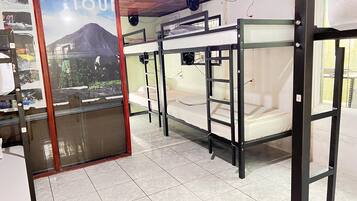 A room with bunk beds, a poster advertising a hiking tour, and a tiled floor.