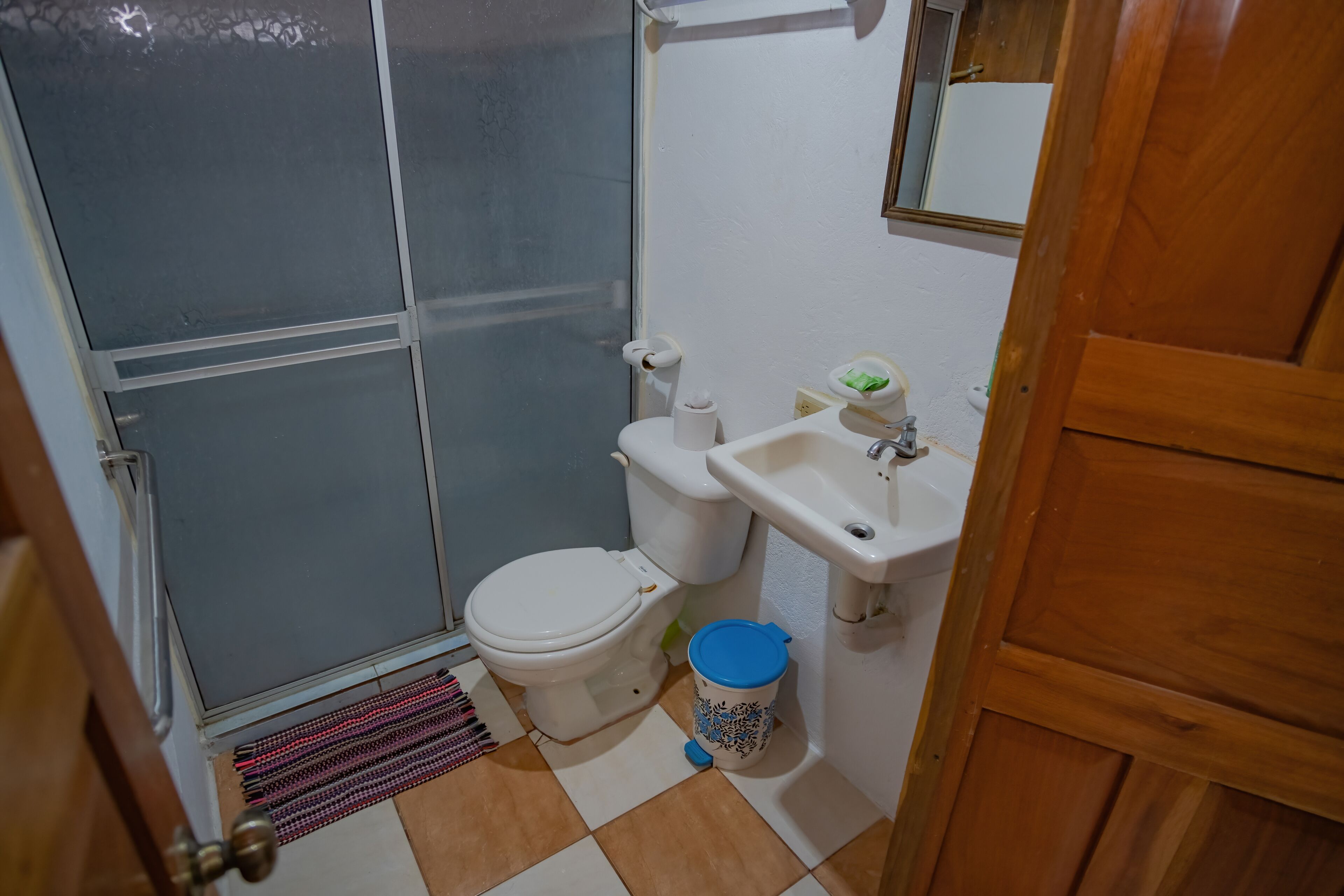 A bathroom with a toilet, sink, and a trash bin.