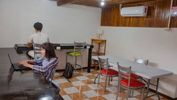 Una habitación con una mesa larga, sillas y una persona usando una computadora portátil.