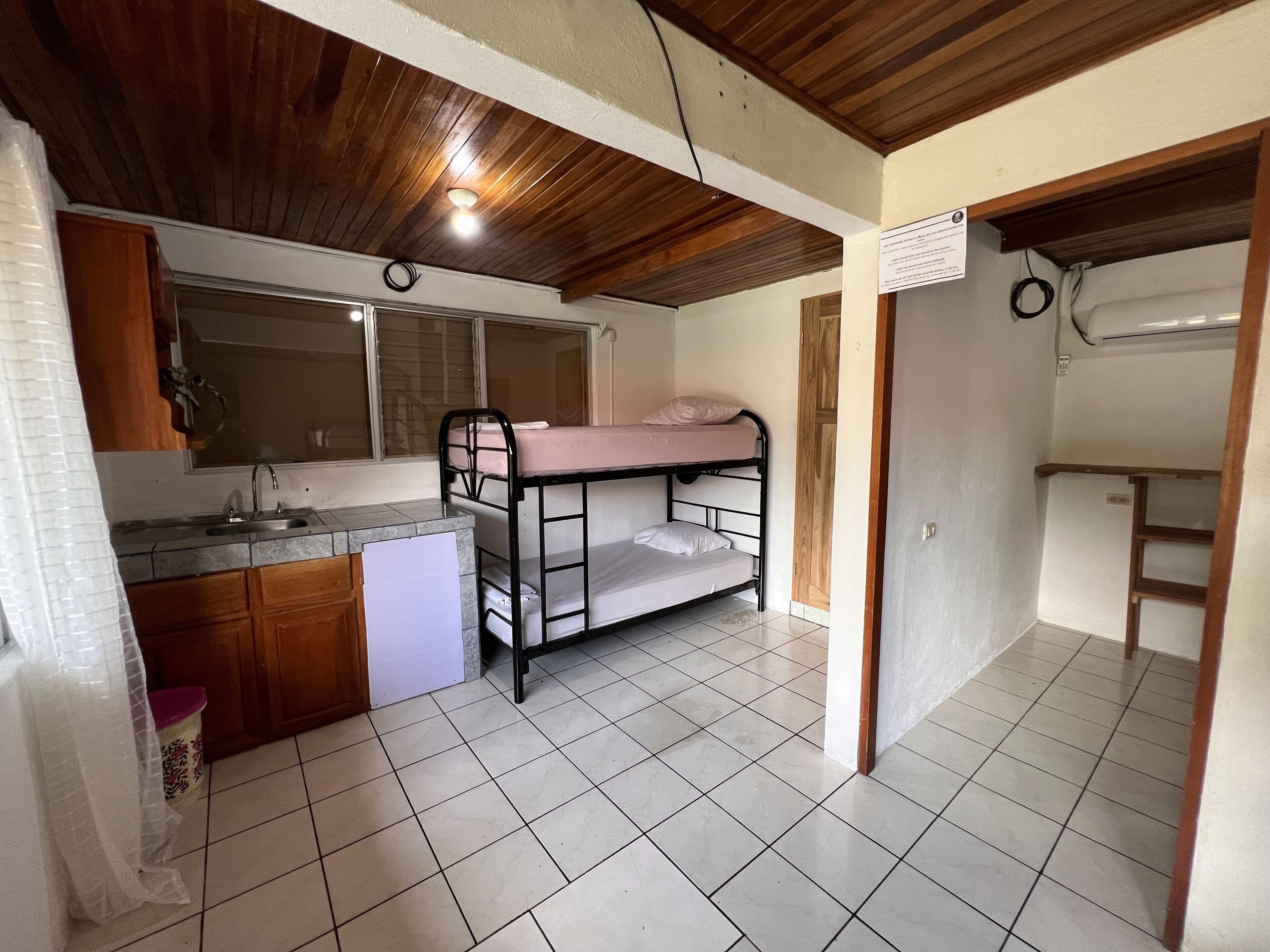 A compact room with a bunk bed, a kitchenette, and a small bathroom.