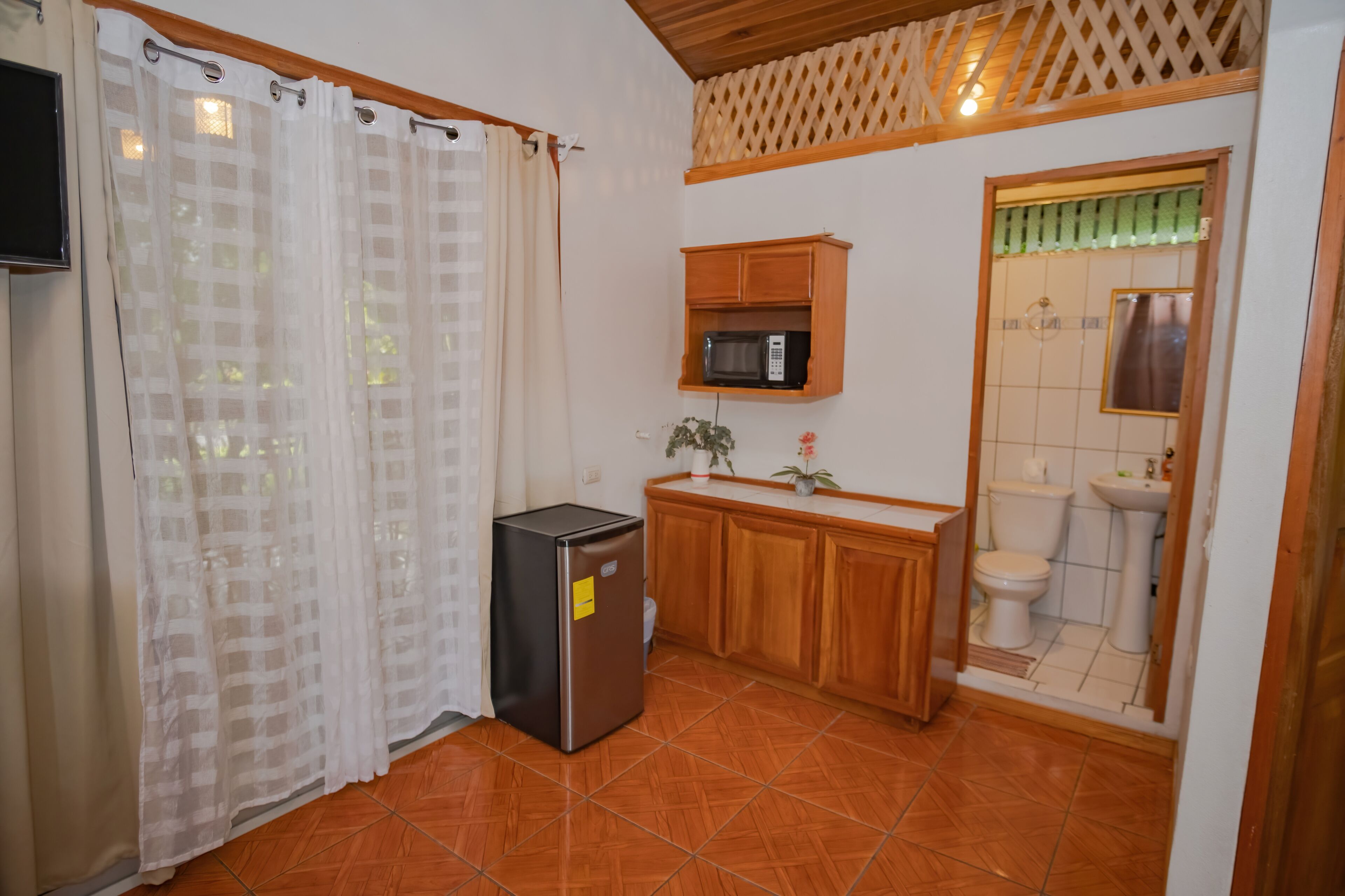 A compact kitchen with a refrigerator, microwave, and wooden cabinets.