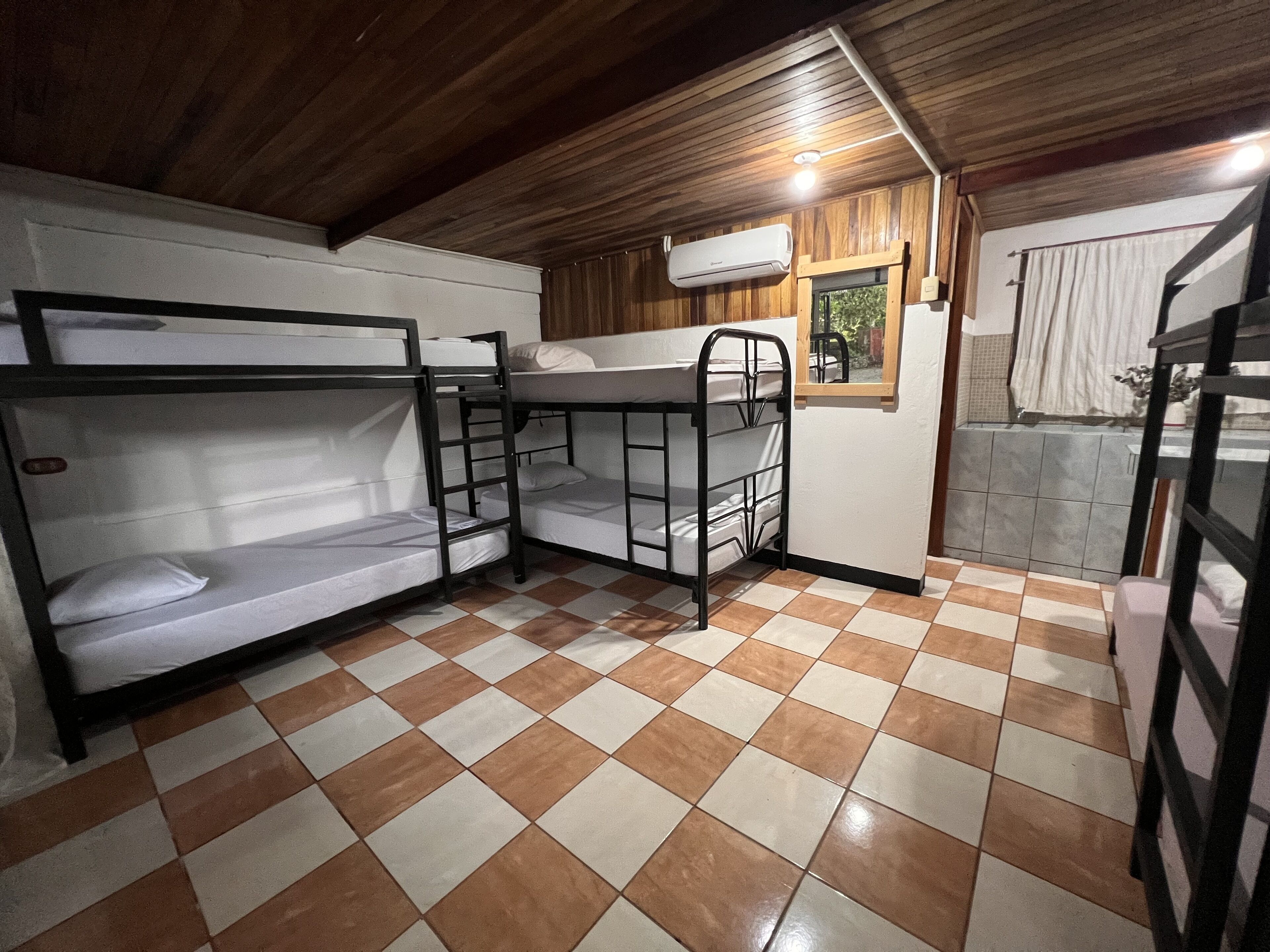 Ein Zimmer mit Etagenbetten, Fliesenboden und einem fenster mit Vorhängen.