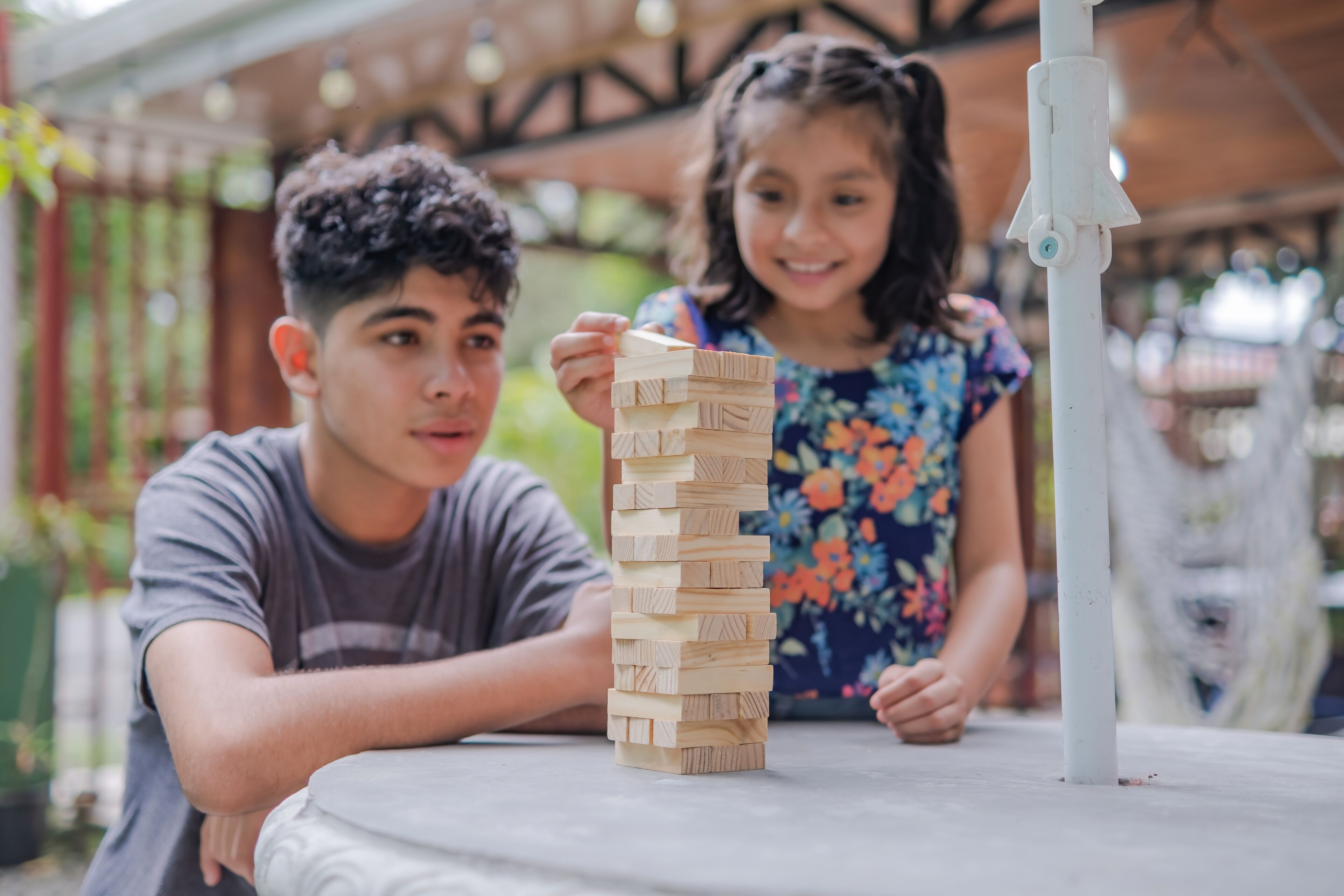 Two people playing a wooden block game at a table.