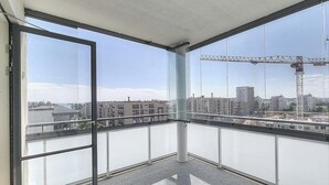 A balcony with large windows overlooking a cityscape, including buildings and a construction crane. - Nice apartment with sea view<br> (Helsinki)