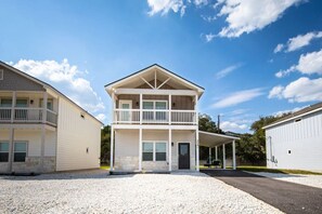 A two-story building with a balcony on the upper floor, a covered front porch, and a gravel driveway. - 41 · Amazing location rent 1,2 or all 3 homes available (Canyon Lake)