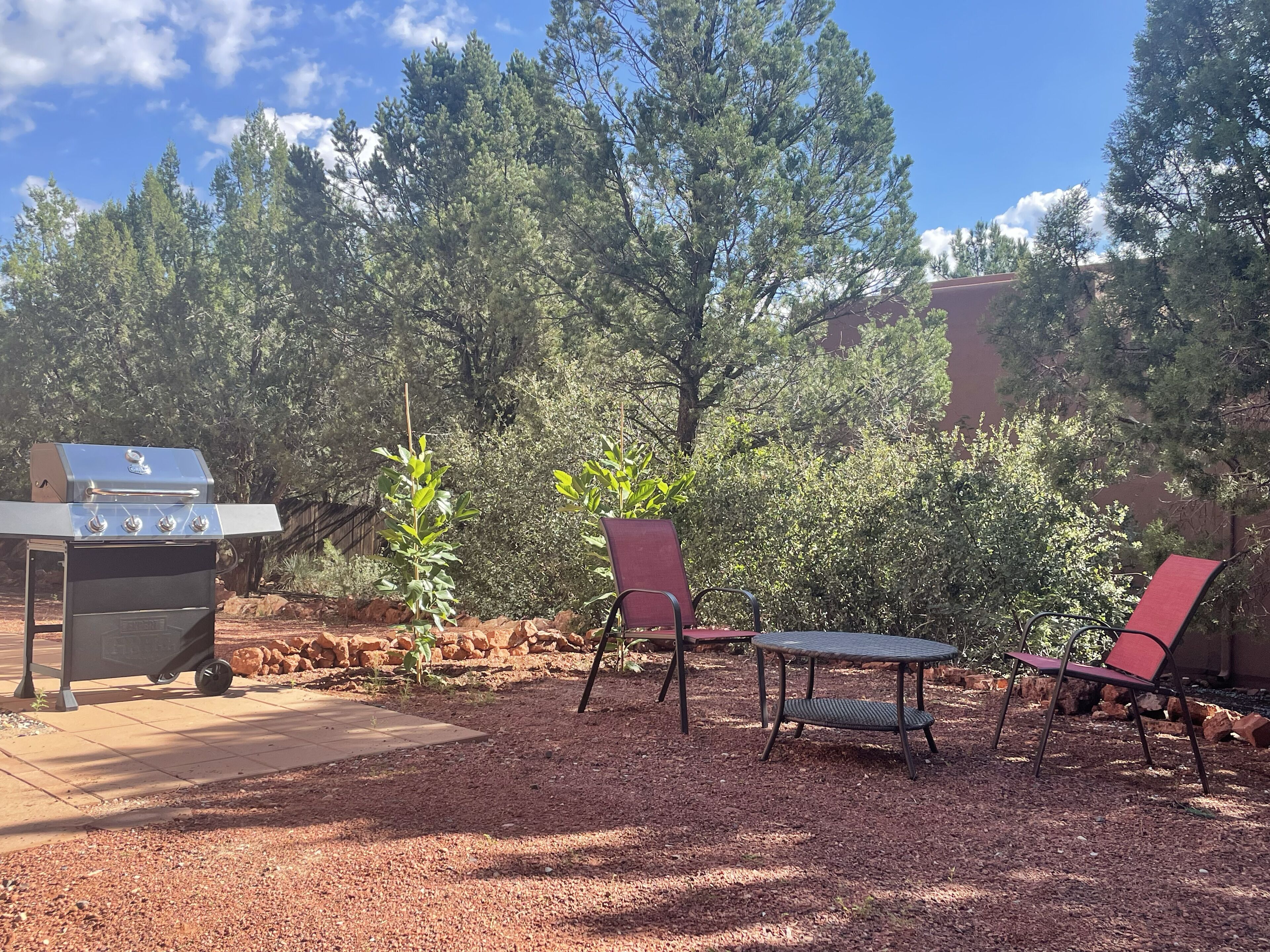 Eine Terrassenausstattung mit Grill, zwei Stühlen und einem Tisch.