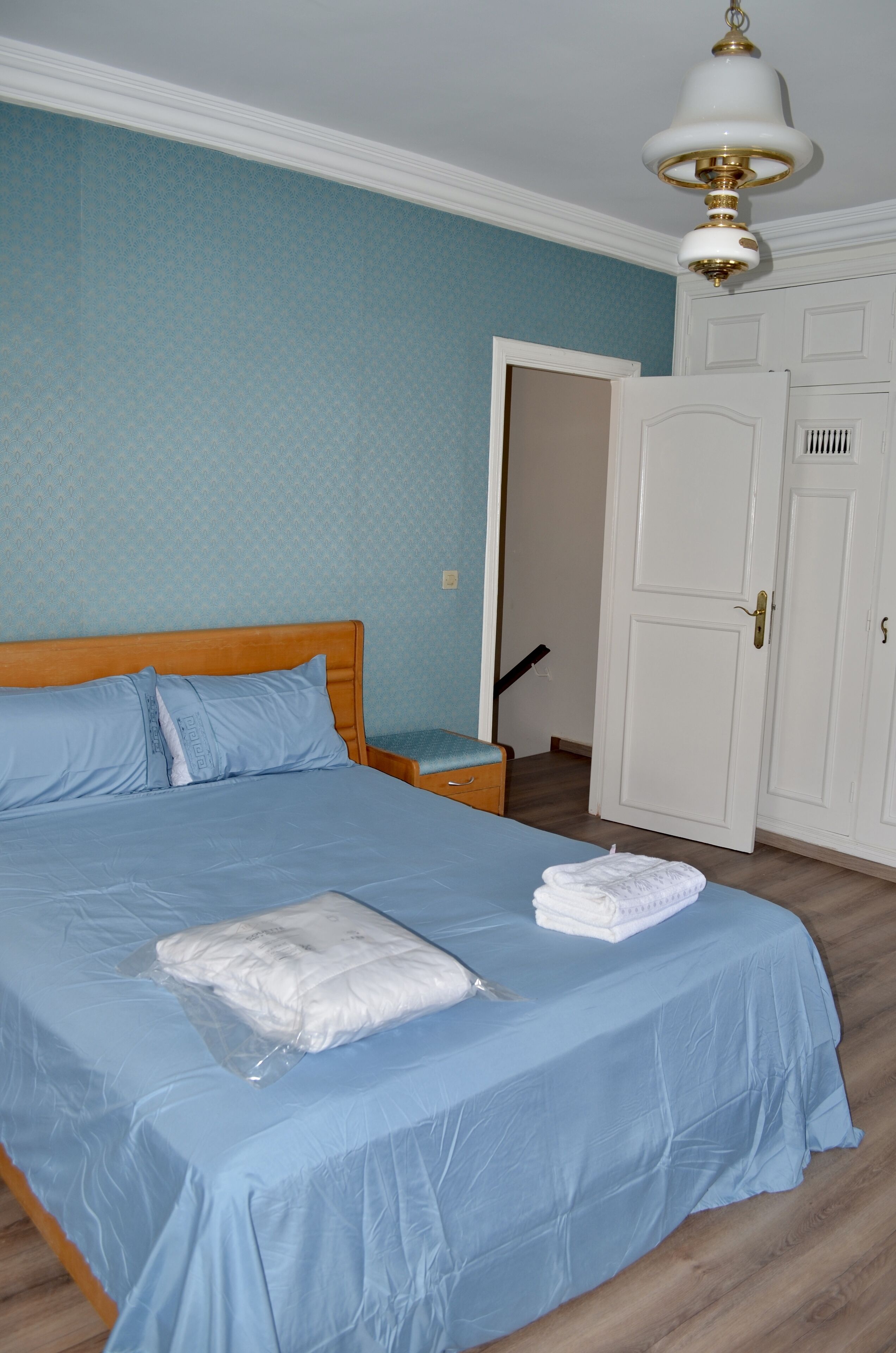 A bedroom with a bed, a nightstand, a wardrobe, and a door.