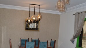 Un coin repas avec des chaises et une table en bois, un canapé avec des coussins et un luminaire suspendu.
