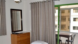 Une chambre à coucher avec un lit, une commode, un miroir et une vue sur l’extérieur.
