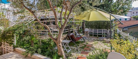 Un jardín con una hamaca, un columpio y una silla blanca.