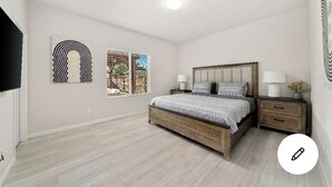 A bedroom with a bed, two bedside tables, a window with a city view, and artwork on the walls. - cheerful 4 bedroom with beautyfull back yard (Elk Grove)