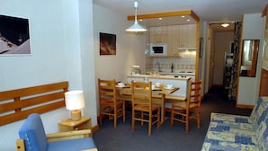 Un espacio habitable compacto con comedor, kitchenette y zona de estar.
