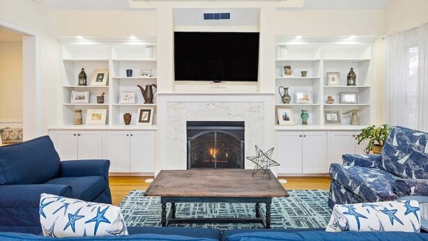 A living room with a fireplace, a flat-screen TV, and built-in shelving with decorative items.