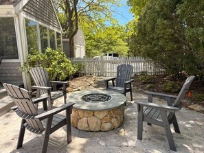 Un espace extérieur aménagé avec des chaises Adirondack et un foyer en pierre.