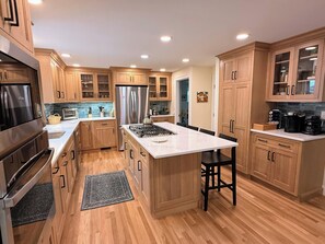 Una cocina moderna con armarios de madera, electrodomésticos de acero inoxidable y una isla de mármol.