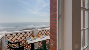 Un balcon avec une table préparée pour le petit-déjeuner, donnant sur l’océan.