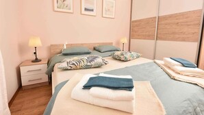 Ein ordentlich bezogenes Bett mit Kissen, ein Nachttisch mit Lampe und ein Spiegel.