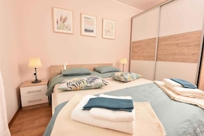 Ein ordentlich bezogenes Bett mit Kissen, ein Nachttisch mit Lampe und ein Spiegel.