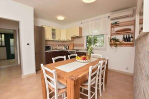 A modern kitchen with white cabinets, a dining table with chairs, and a fruit bowl.