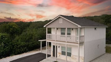 A two-story building with a balcony on the upper floor, a garage entrance, and a driveway leading to the front.