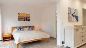 Ein Schlafzimmer mit einem hölzernen Bett, einem Nachttisch, einer Kommode und zwei Wandleuchten.