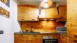 A kitchen with wooden cabinets, a stainless steel sink, a microwave, and an oven. - Cosy apartment for 5 guests with WIFI, hot tub and TV (Canazei)