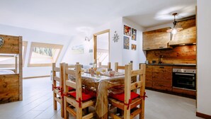 A modern kitchen with wooden cabinets, a dining table with chairs, and a view of the outdoors through skylights. - Cosy apartment for 5 guests with WIFI, hot tub and TV (Canazei)