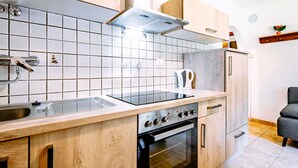 Et moderne køkken med træskabe, en stålvask, indbygget ovn og et flisebeklædt bagpanel.
