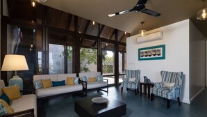 Un salon moderne avec un canapé, des fauteuils, une table basse et un ventilateur de plafond.