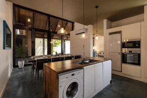 A modern kitchen with a built-in washer, a dining area with natural light, and a large island with a sink. - Inidi Leisure exemplifies luxury travel in Sri Lanka (Wadduwa)