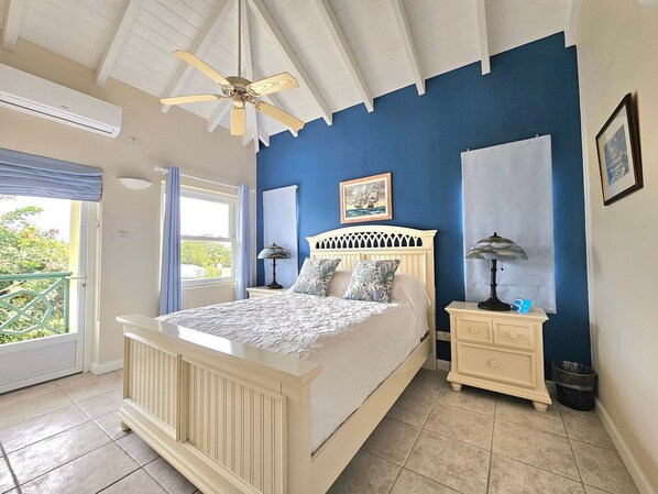 A bedroom with a bed, nightstands, a ceiling fan, and a window with curtains.