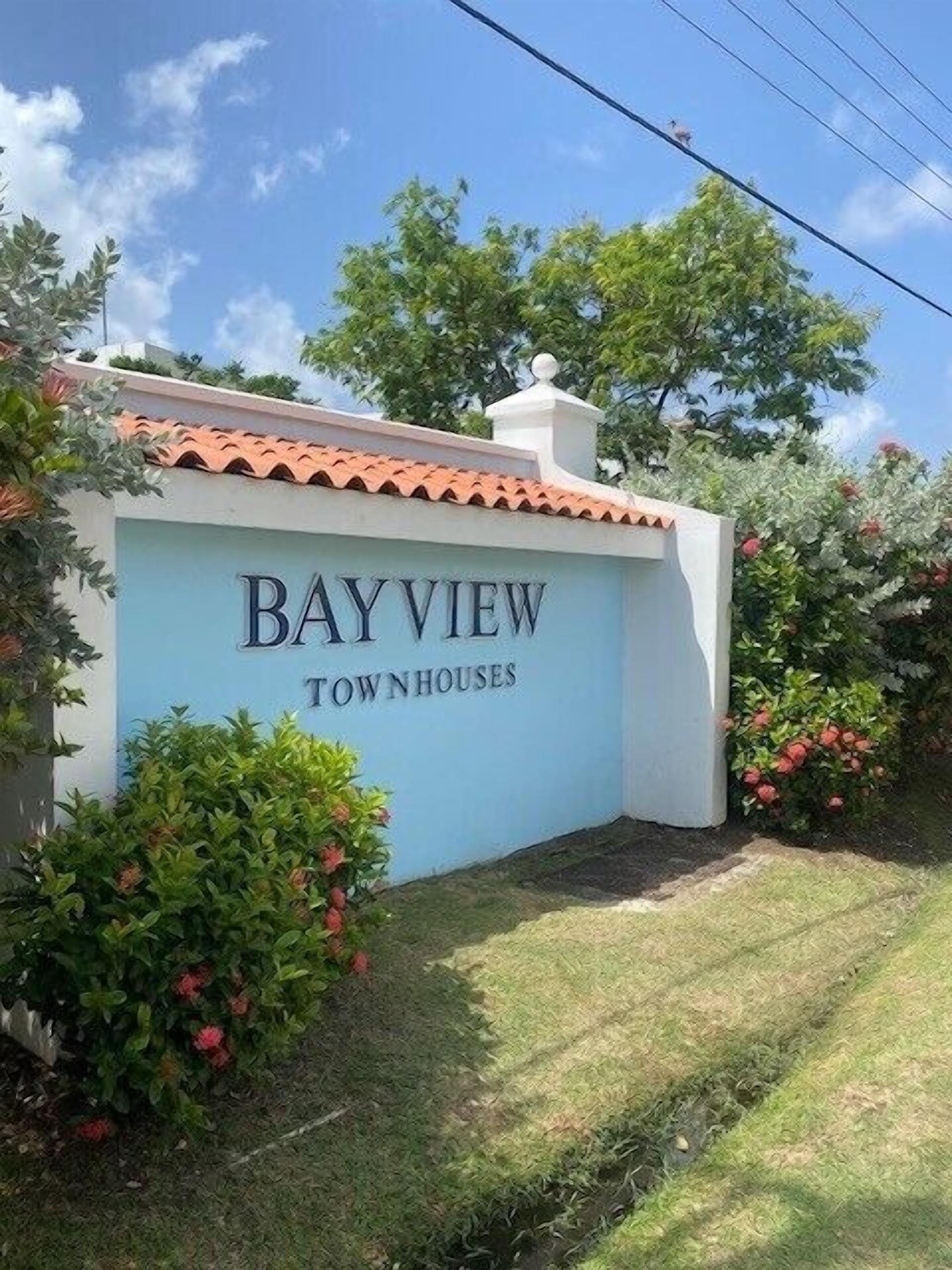 Naamplaatje voor Bayview Townhouses, met een betegeld dak en omringd door groen.
