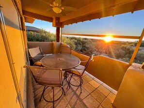 Ein Balkon mit Tisch und Stühlen mit Blick auf eine malerische Landschaft bei Sonnenuntergang.