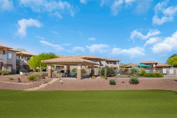A residential complex with multiple houses, a covered patio, and a well-maintained lawn.
