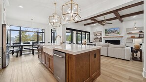 Una cocina amplia con armarios de madera, una isla central y ventanas grandes que ofrecen vistas al exterior.